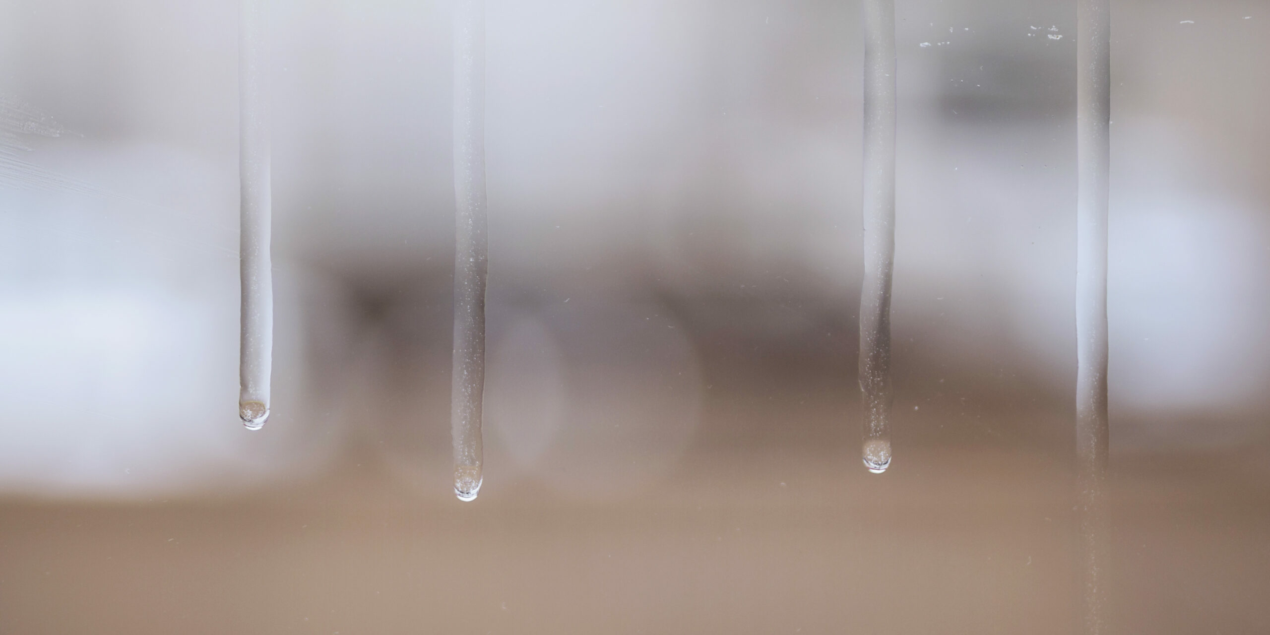 Image de gouttes d'eau ruisselant sur le carreau d'une fenêtre.